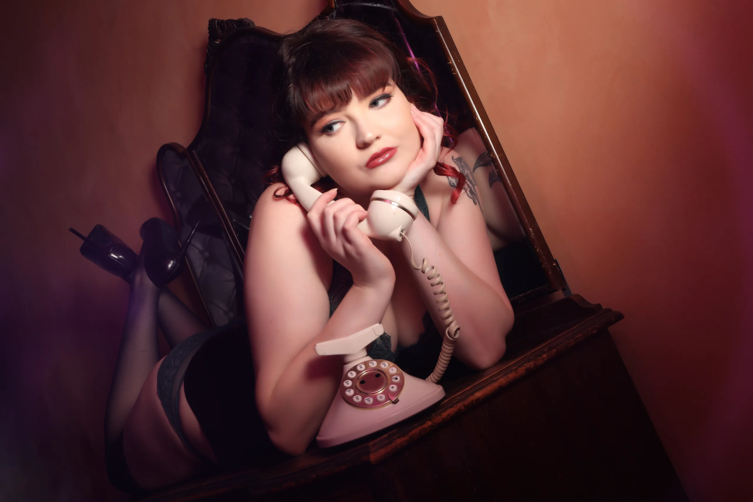 Woman on a table posing for a boudoir photoshoot with vintage phone
